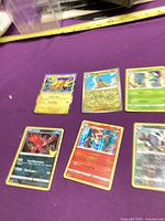 Six Pokémon holographic cards spread on purple surface