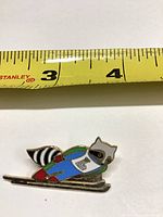 Front of enamel pin with tape measure showing length