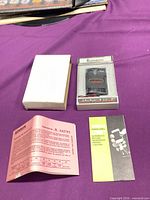 Full lot showing lighter in display case, outer white sleeve box and paperwork