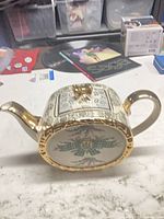 Side view of Sadler porcelain teapot showing gold gilt handle, spout, crest panel and floral design