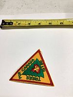 Front view of embroidered triangle patch with measuring tape showing size