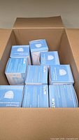 Open shipping carton showing nine sealed blue Norcoguard mask boxes