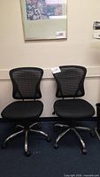 Two black mesh office chairs side by side showing full design