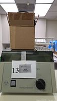 Front view showing brand, model, cardboard box resting on lid