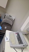 Brother electronic typewriter on desk with chairs behind