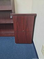 Front view of mahogany two-drawer filing cabinet next to wall