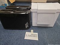 Two black Tork dispensers and one white bin on floor