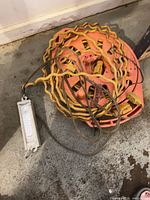 Extension cord wound on orange plastic reel with scale lying beside it