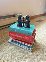 Opera glasses resting on stack of books displaying overall size