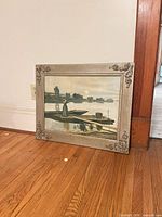 Framed oil painting leaned against wall showing full view
