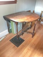 Full view of drop-leaf table with one leaf down showing turned legs and oval shape