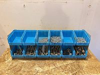 Front view of eight blue bins filled with assorted small screws and bolts