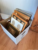 box containing multiple wood and metal picture frames