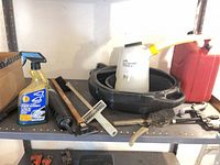 Shelf holding oil drain pan, fluid container with funnel, spray car wash bottle, various hand tools