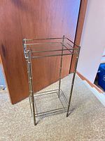 Full view of brass-tone metal frame table with two glass shelves