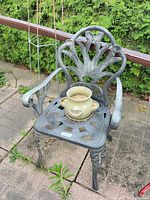 Full view of cast metal patio chair with planter and saucer placed on seat