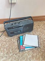Citizen boombox with stack of blank CD-Rs and jewel cases on carpet