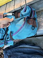 Teal backpack top pocket showing leather tabs and zipper