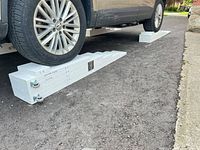 Vehicle parked on one of the white wooden ramps, full view of both ramps on driveway