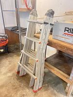 Full view of folded Featherlite articulating ladder leaning against shelf