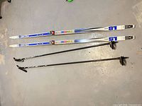 Full view of Fischer skis and poles laid on floor