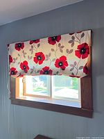 Roman shade installed on window showing floral pattern and corded lift