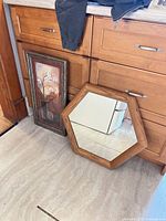 Octagon mirror and floral art leaning against cabinet