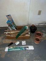Group shot of all garden items on floor including fleece roll, timers, nozzle, saucers, stakes, burlap