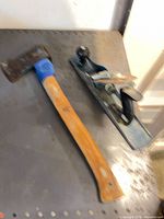 Hatchet and hand plane on metal surface