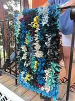 Full view of handmade multicolor hooked rag rug held vertically