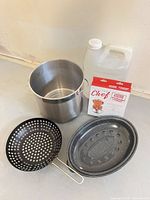 Group shot showing stock pot, grill basket, enamel roaster, boxed chicken roaster, plastic jug