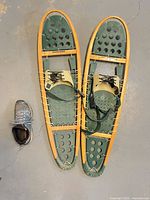 Top view of both snowshoes beside a shoe for scale