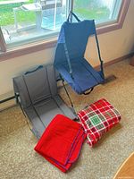 Two open stadium seats (gray and navy) plus two blankets on floor
