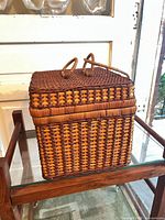 Closed wicker picnic basket on glass shelf