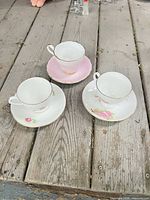 Top view of three teacup and saucer sets on wood surface