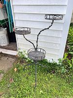 Full view of three-tier wrought iron plant stand outdoors
