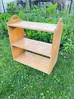 Front view of plywood bookcase showing three shelves and cut-out handles