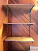 Full view of wall-mounted shelving unit with three shelves attached to metal tracks