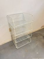 Full view of four-tier white wire basket unit against wall