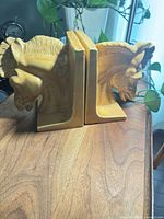 Front view of both mustard yellow ceramic horse head bookends standing upright