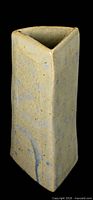 Side view of tall rectangular stoneware vase with folded triangular opening, cream glaze with blue accents