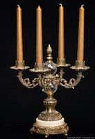 Full view of ornate brass and crystal four-light candelabra with taper candles inserted, showing detailing and marble base