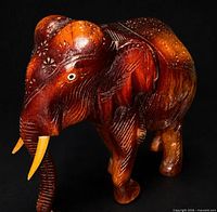 Full view of carved wooden elephant showing shape, tusks, and overall finish