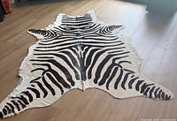 Full view of faux zebra hide rug lying flat on floor, showing stripe pattern and hide shape