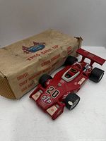 Red ceramic race car decanter beside original cardboard box