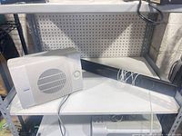 Subwoofer and soundbar on shelf showing overall condition and cables