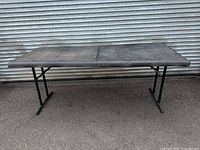 Full view of rectangular black folding table standing on metal legs