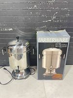 Coffee urn with power cord and box beside it