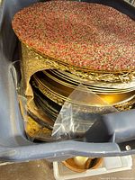 Stack of gold charger plates and red woven placemats in bin