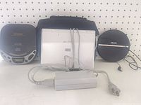 GO.VIDEO DVD player centered with Koss and Philips CD players, power brick in foreground, carry bag behind